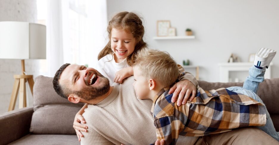 Junge Familie lacht auf der Couch.