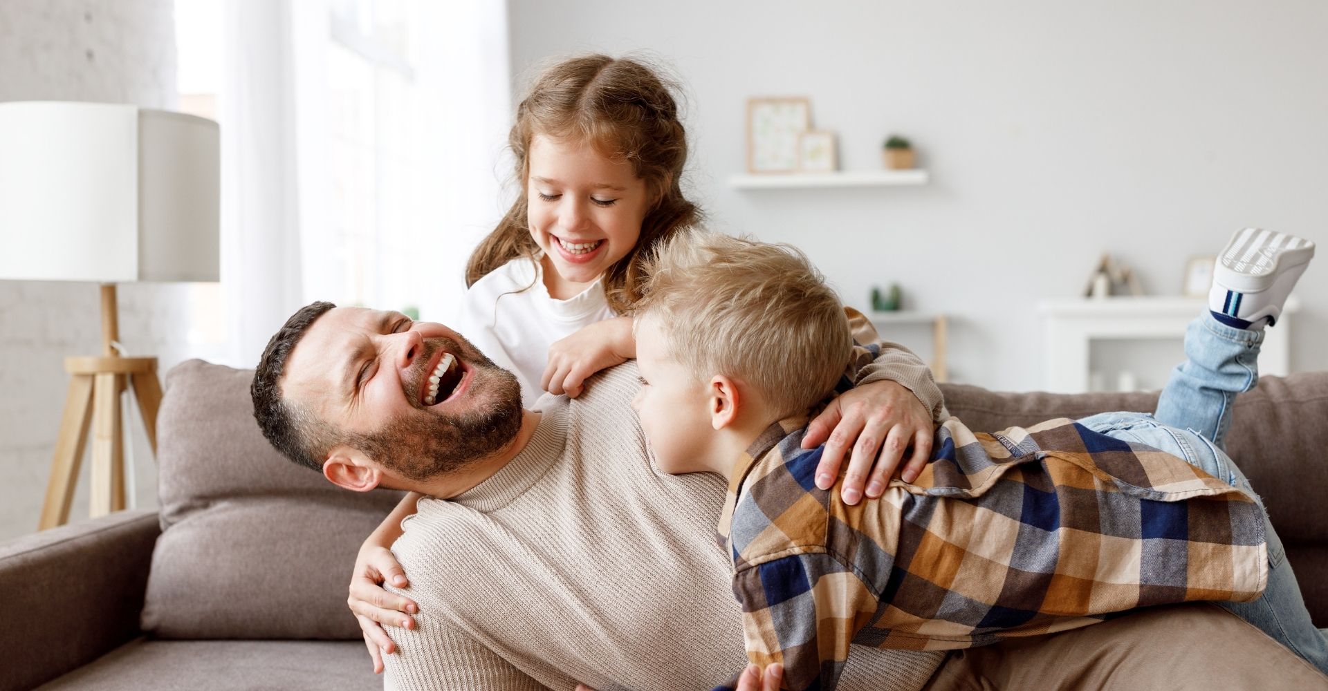 Junge Familie lacht auf der Couch.