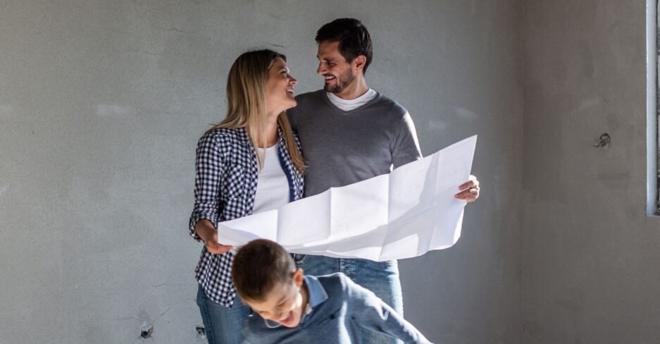Junge Familie in Rohbau mit Plan in der Hand.