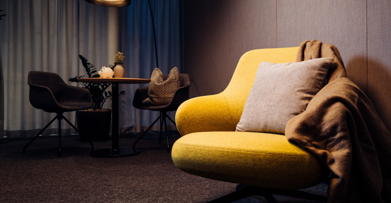 Lounge mit gelbem Sessel – ein sicheres Zuhause dank Hausbau-Finanzierung & individueller Wohnbauförderung in Tirol.