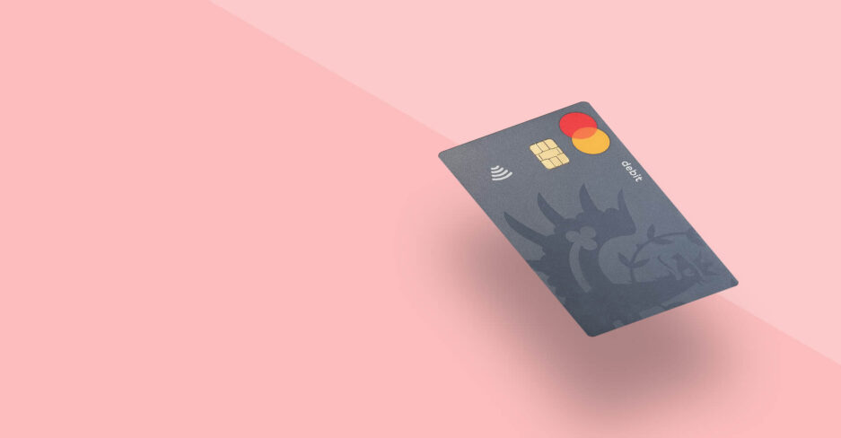 Blaue Mastercard-Debitkarte der Hypo Tirol mit kontaktlos-Symbol schwebt vor rosa Hintergrund.
