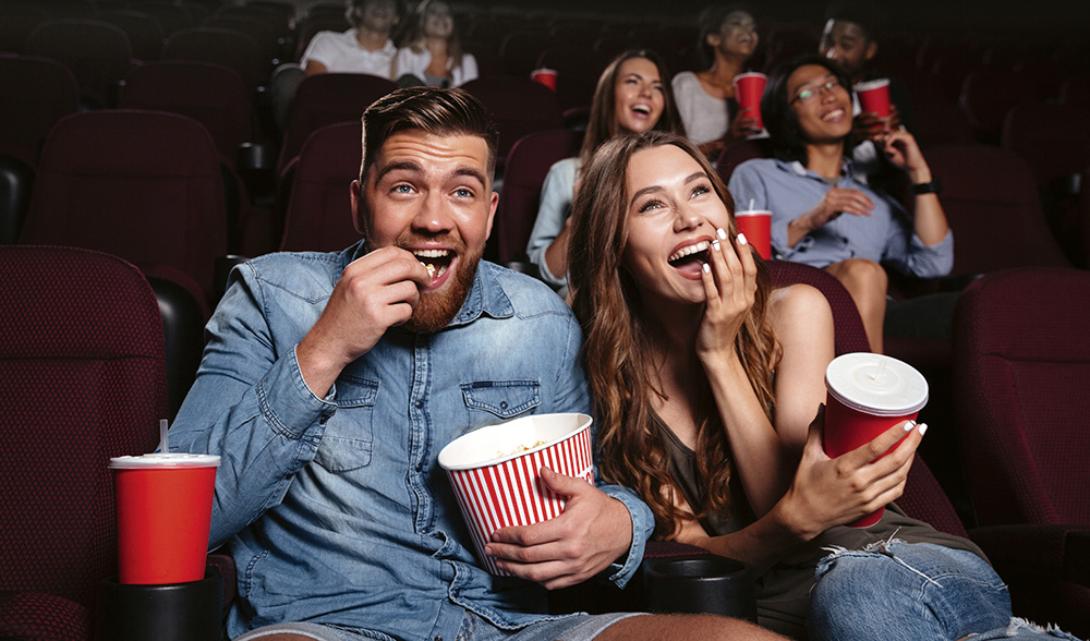 Kinosaal im Metropol Multiplex mit Menschen, die Popcorn und Getränke halten und lachen