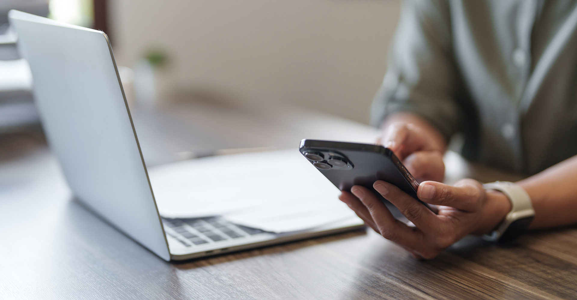 Person mit Smartphone und Laptop – ePIN im Internetbanking einfach abrufen