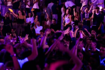 Menschen auf einer Party tanzen mit Händen in der Höhe auf einer Tanzfläche.