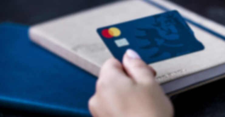 Hypo Debitkarte wird in Hand gehalten, dahinter ein Notizbuch.