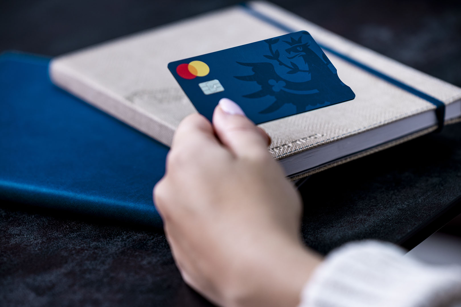 Frauenhand hält die Hypo Tirol Debitkarte mit sogenanntem blind notch, einer Einkerbung für blinde und sehbehinderte Menschen