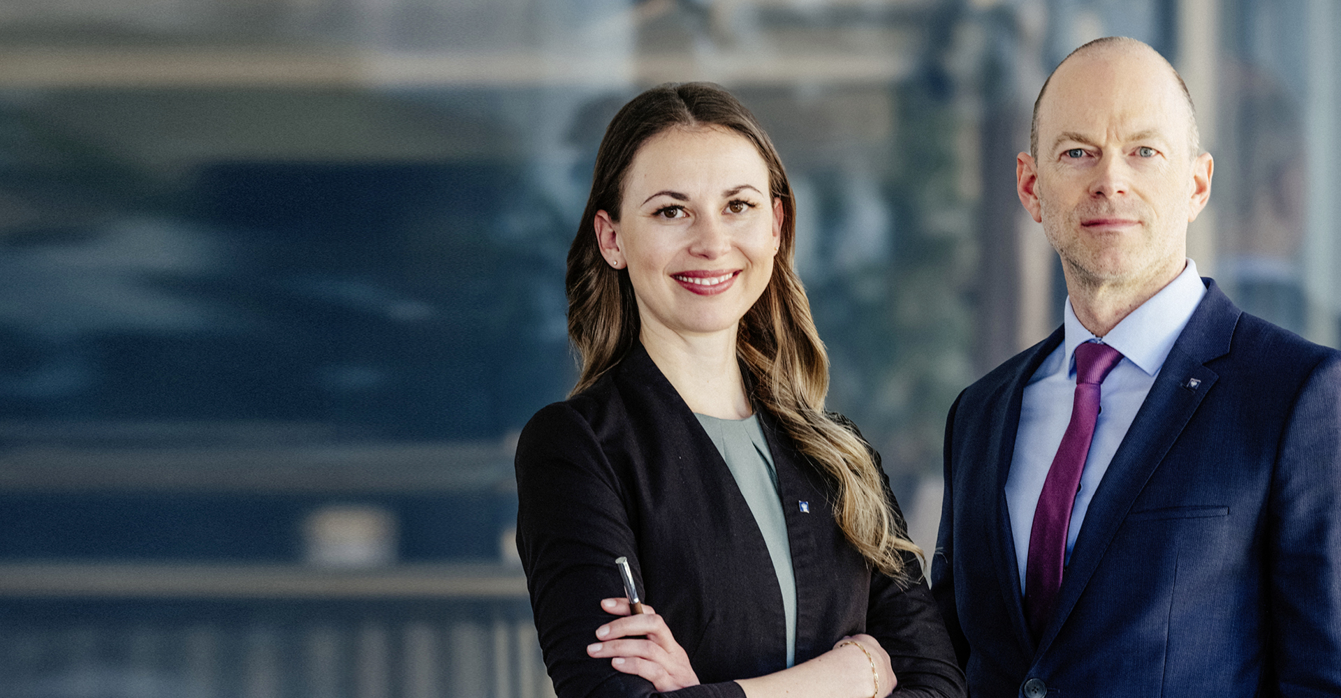 Zwei Berater der Hypo Tirol stehen nebeneinander im Büro – Symbol für Dualbetreuung von Firmenkunden und Private Banking