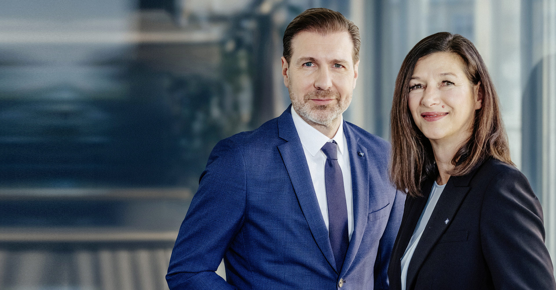 Zwei Berater der Hypo Tirol stehen nebeneinander im Büro – Symbol für Dualbetreuung von Firmenkunden und Private Banking