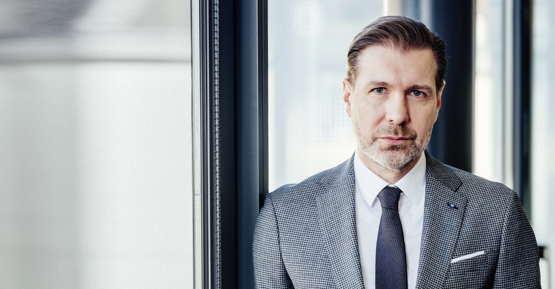 Portrait von Robert Lang, Betreuer im Private Banking in der Hypo Tirol, vor einer Fensterfront