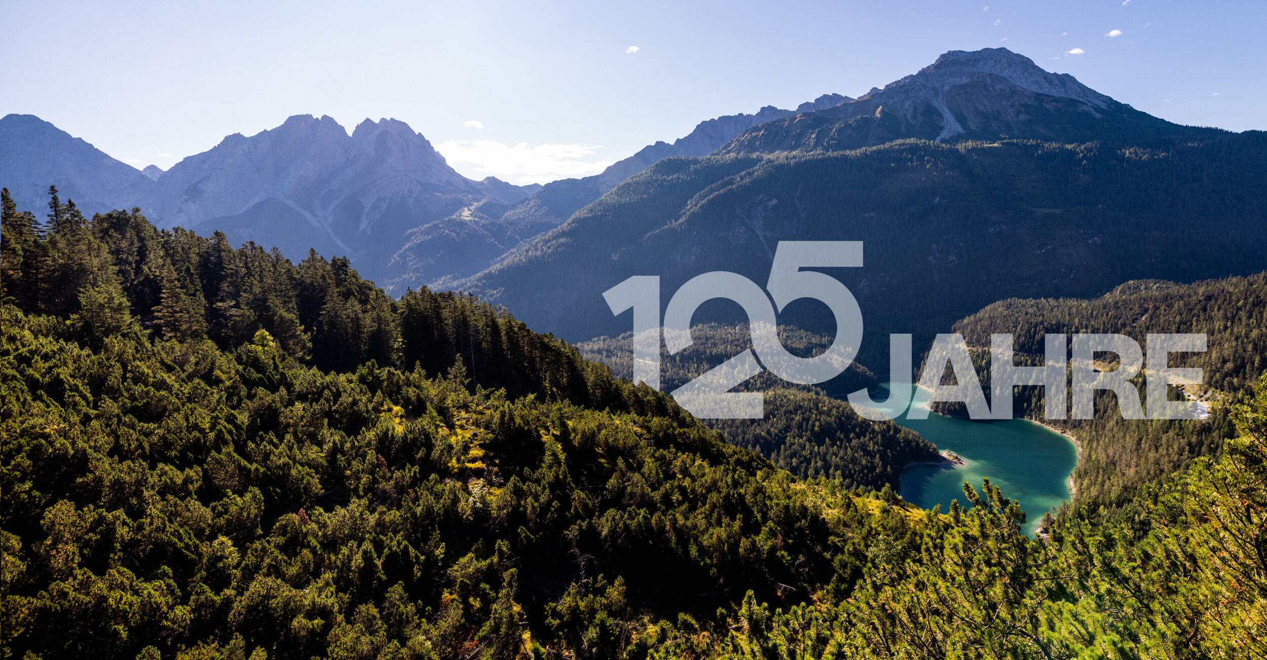 Tiroler Berglandschaft. 125-Jahr-Schriftzug der Hypo Tirol in weiß