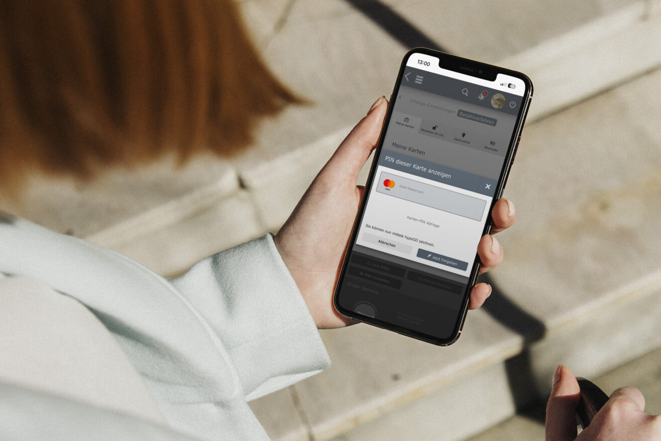 Eine Frau hält ein Smartphone in der Hand, auf dem Bildschirm sieht man eine Oberfläche des Onlinebankings, bei der man den ePIN abfragen kann.