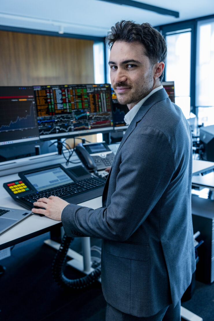 Person arbeitet an einem professionellen Handels‑ oder Steuerungsarbeitsplatz mit mehreren Bildschirmen.