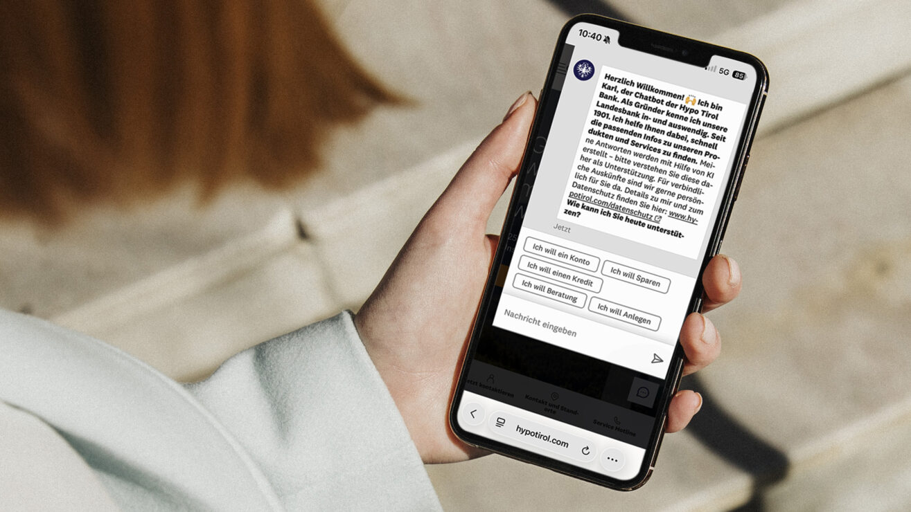 Eine Person hält ein Smartphone mit dem geöffneten Hypo-Tirol-Chatbot Karl in der Hand.