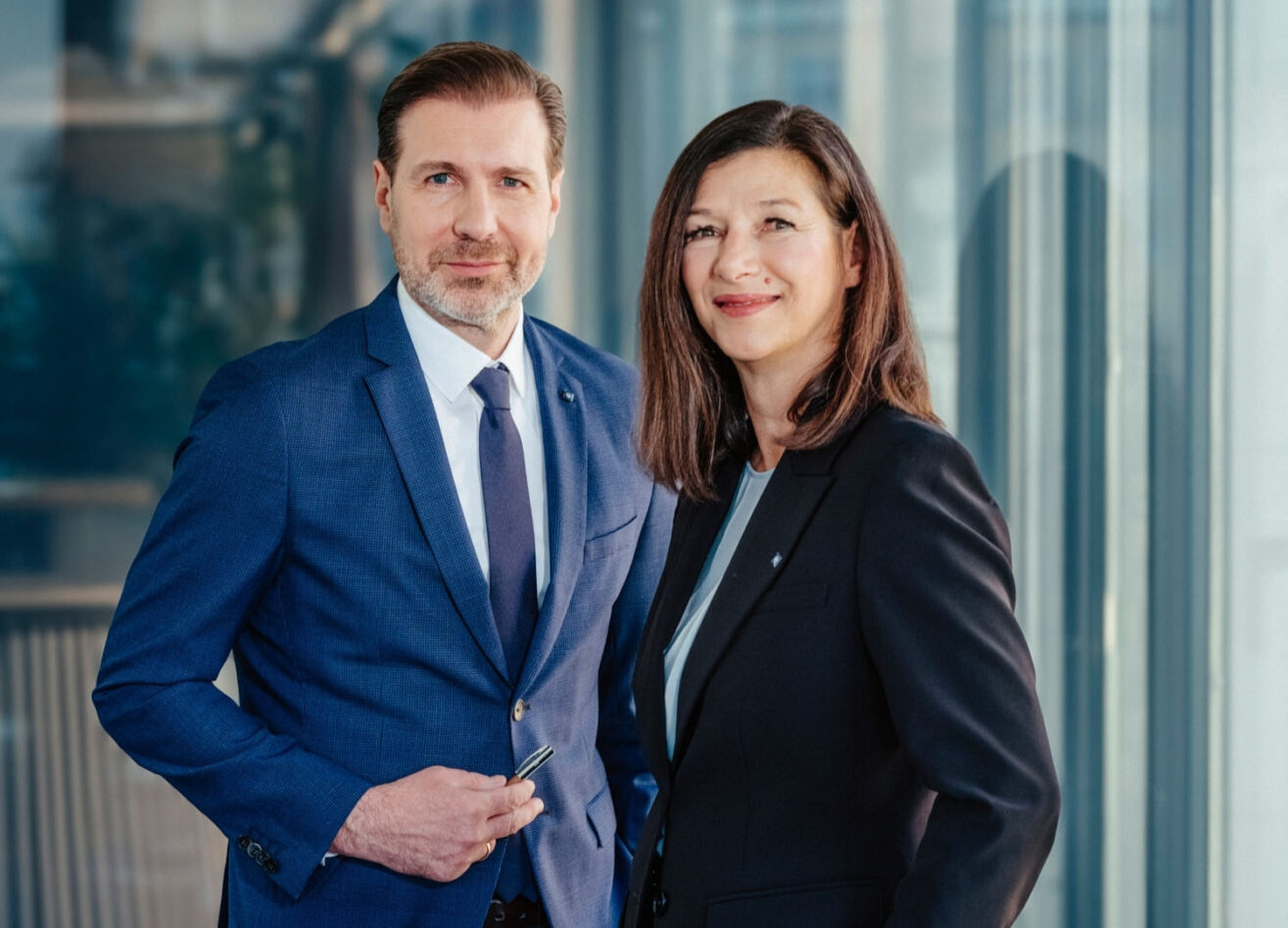 Berater und Beraterin der Hypo Tirol stehen gemeinsam im Büro – Symbol für Dualbetreuung