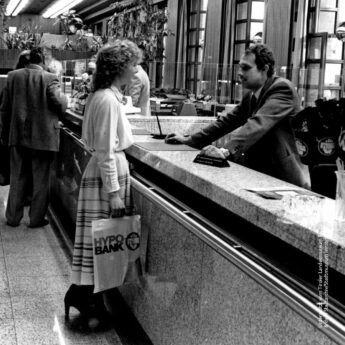 Schwarz-Weiß-Fotografie einer Hypo Tirol Kundin im Gespräch mit einem Mitarbeiter am Schalter