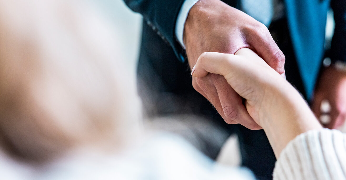 Nahaufnahme zweier Hände, die sich zu einem Handschlag treffen.